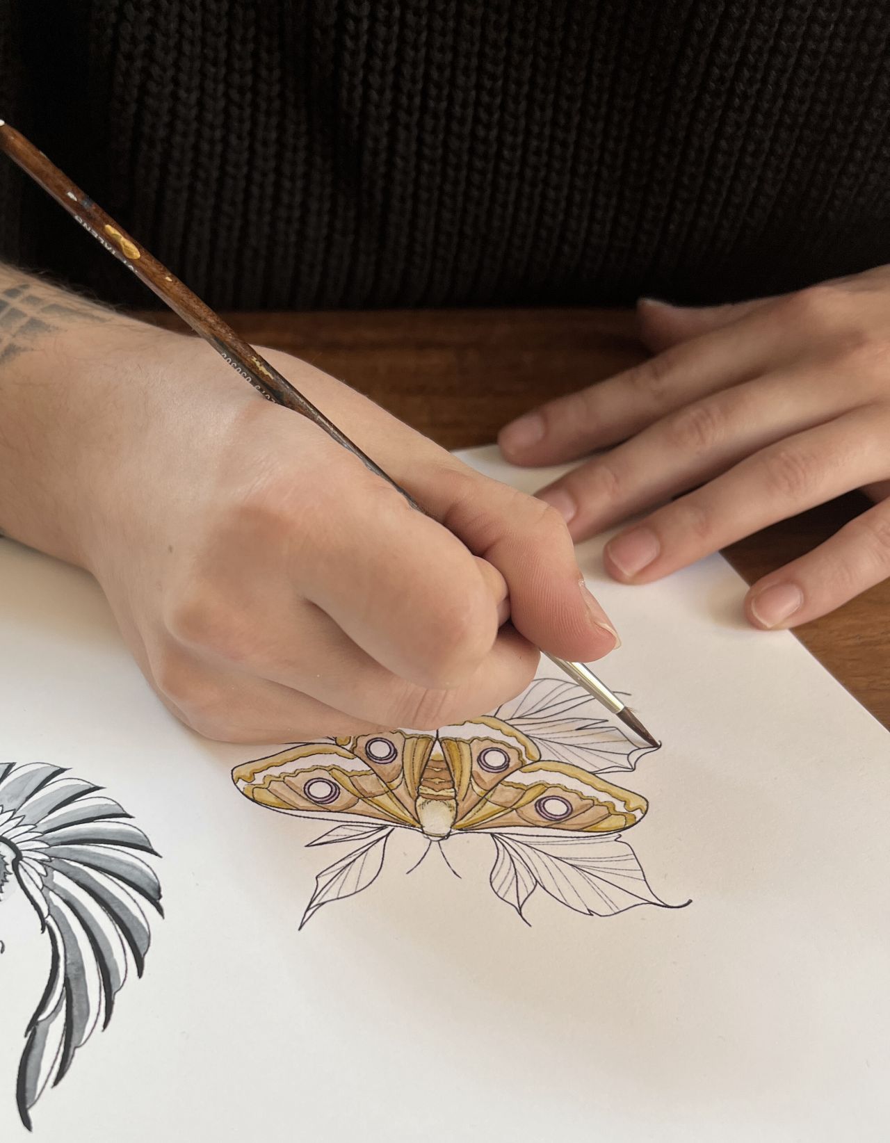 A student coloring a butterfly drawing at Absolut Tattoo Academy.