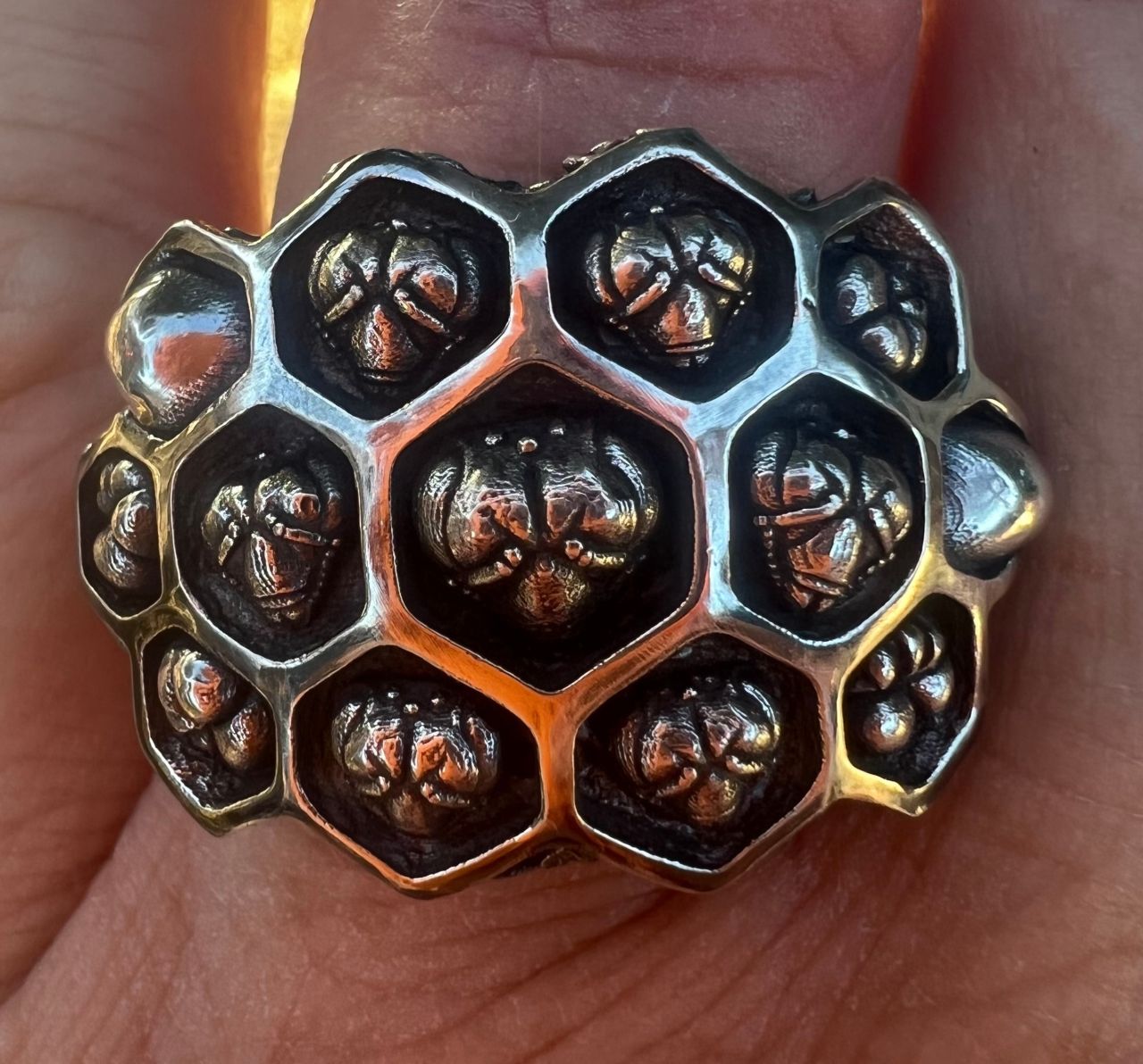 A ring designed like a honeybee hive with bee heads emerging from the cells.